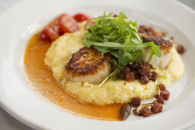 Photo of Sea,Scallops With Cherry Tomato and Chorizo plated on a bed of chorizo